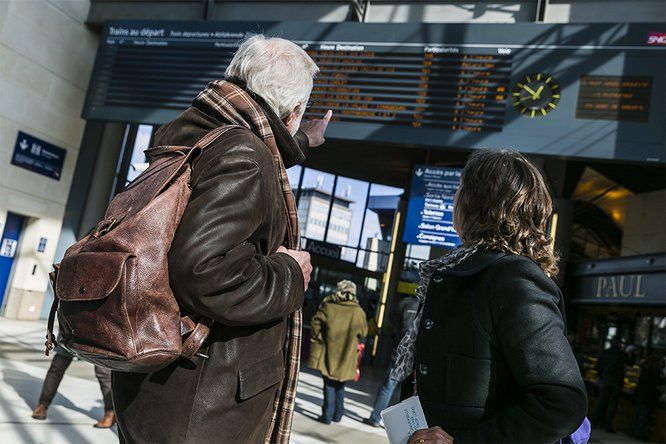 Voyageurs en gare devant affichage des trains au départ