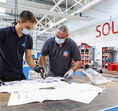 Un homme âgé et son jeune apprenti consultent des plans 